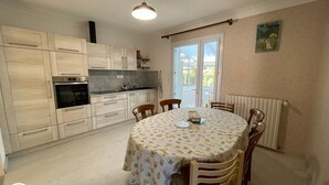 A kitchen with light wood cabinets, a built-in oven, and a dining table with a floral tablecloth.