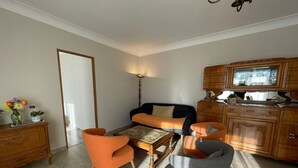 A living room with a sofa, two armchairs, a coffee table, and a wooden cabinet.