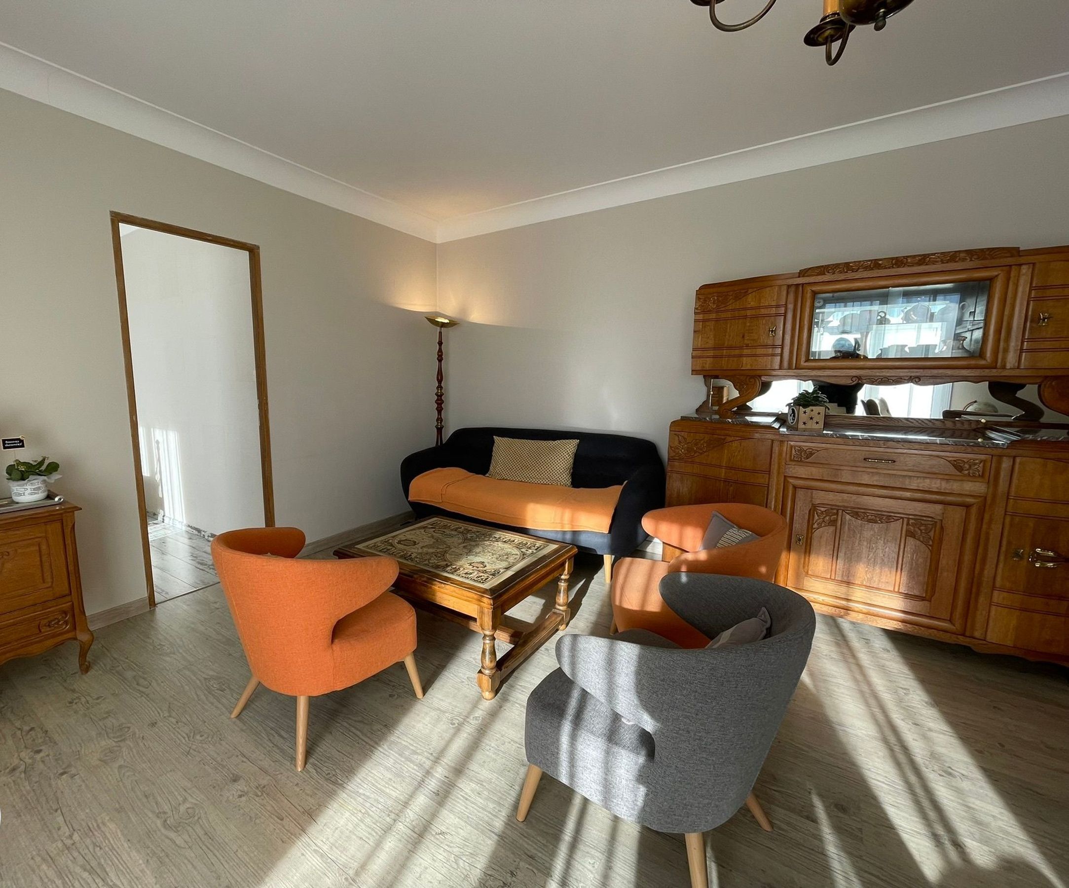 A living room with a sofa, two armchairs, a coffee table, and a wooden cabinet.