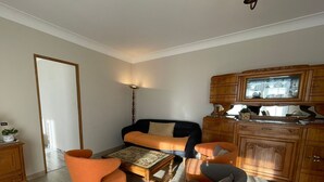 Un salon comprenant un canapé, deux fauteuils, une table basse et un meuble en bois.