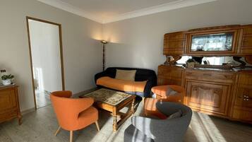 A living room with a sofa, two armchairs, a coffee table, and a wooden cabinet.