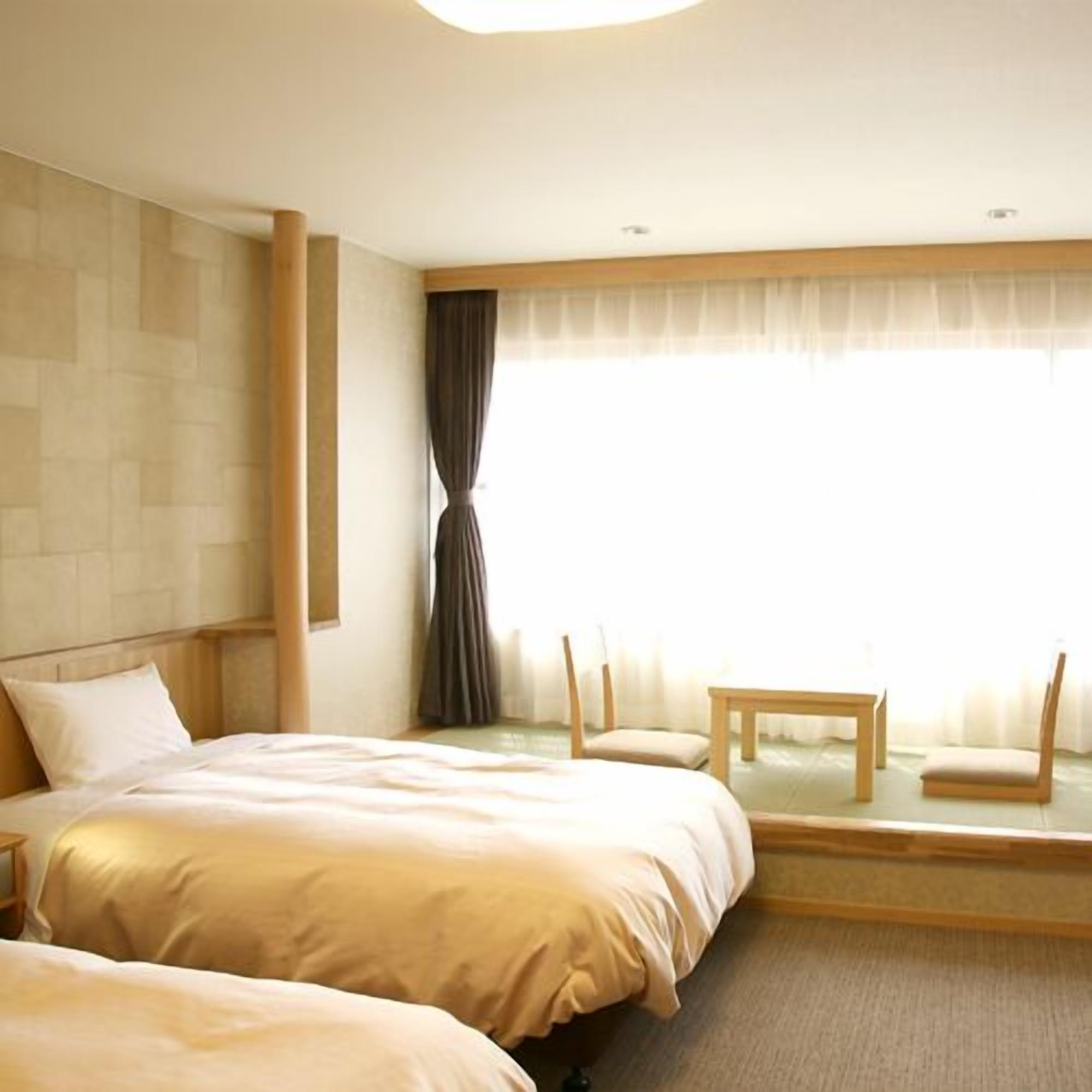 A hotel room with two beds, a small table, and chairs.