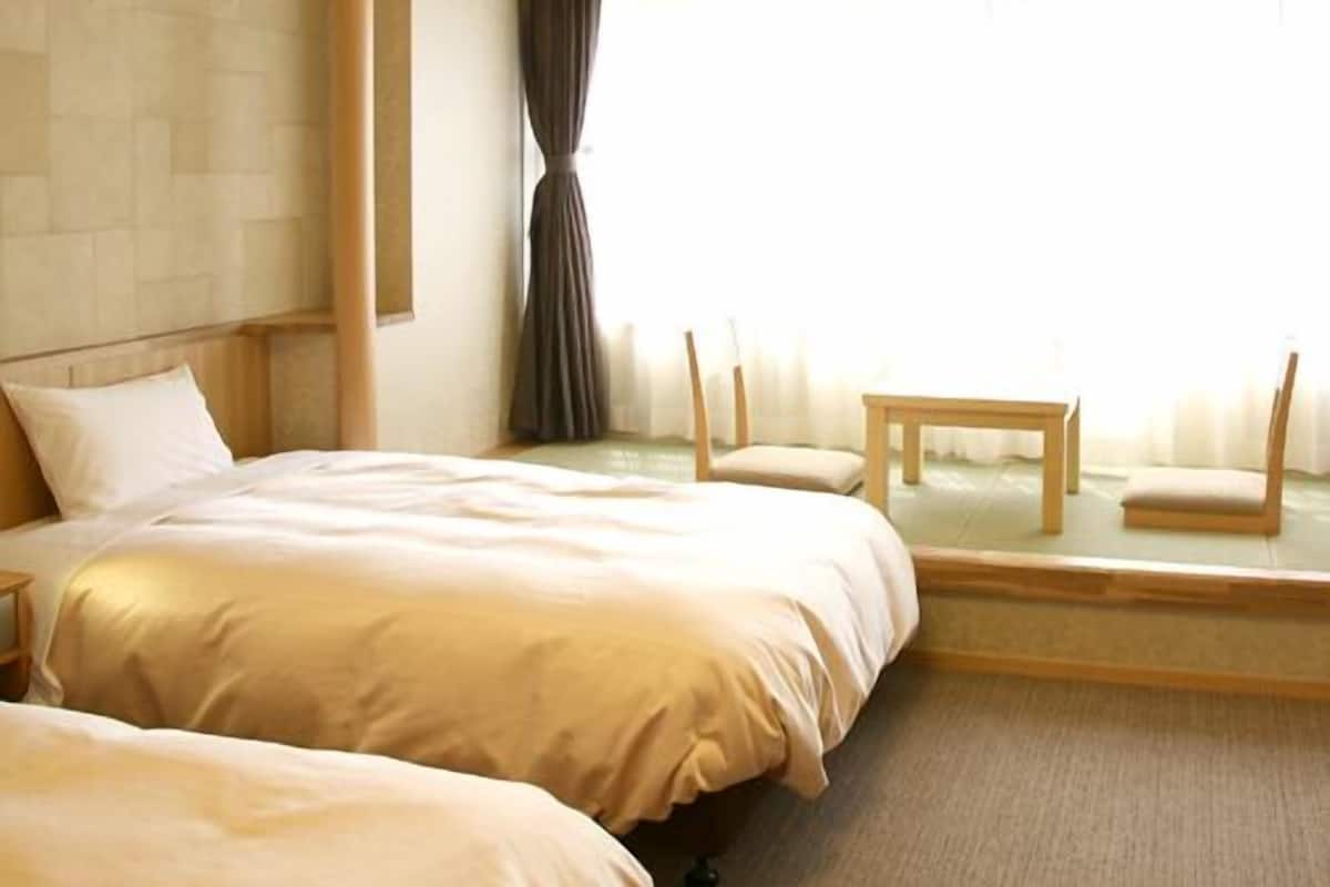 Una habitación de hotel con dos camas, una mesita y sillas.