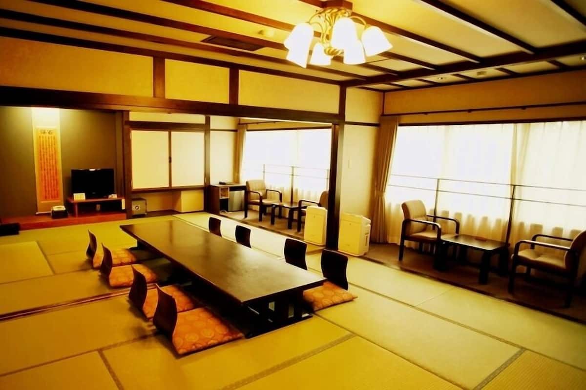 Una habitación tradicional japonesa con suelo de tatami, una mesa larga y sillas.