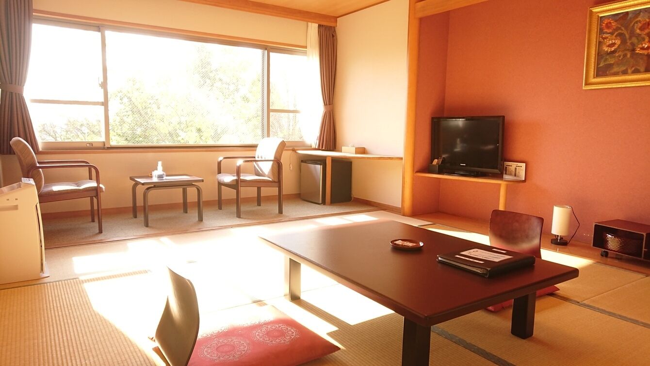 A room with a TV, a desk, a chair, and a table.