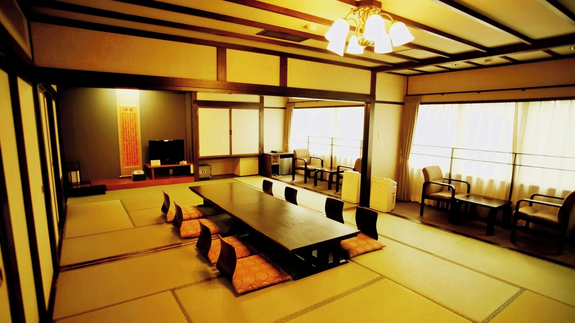 Una habitación de estilo japonés tradicional con suelo de tatami, una mesa larga y varias sillas.