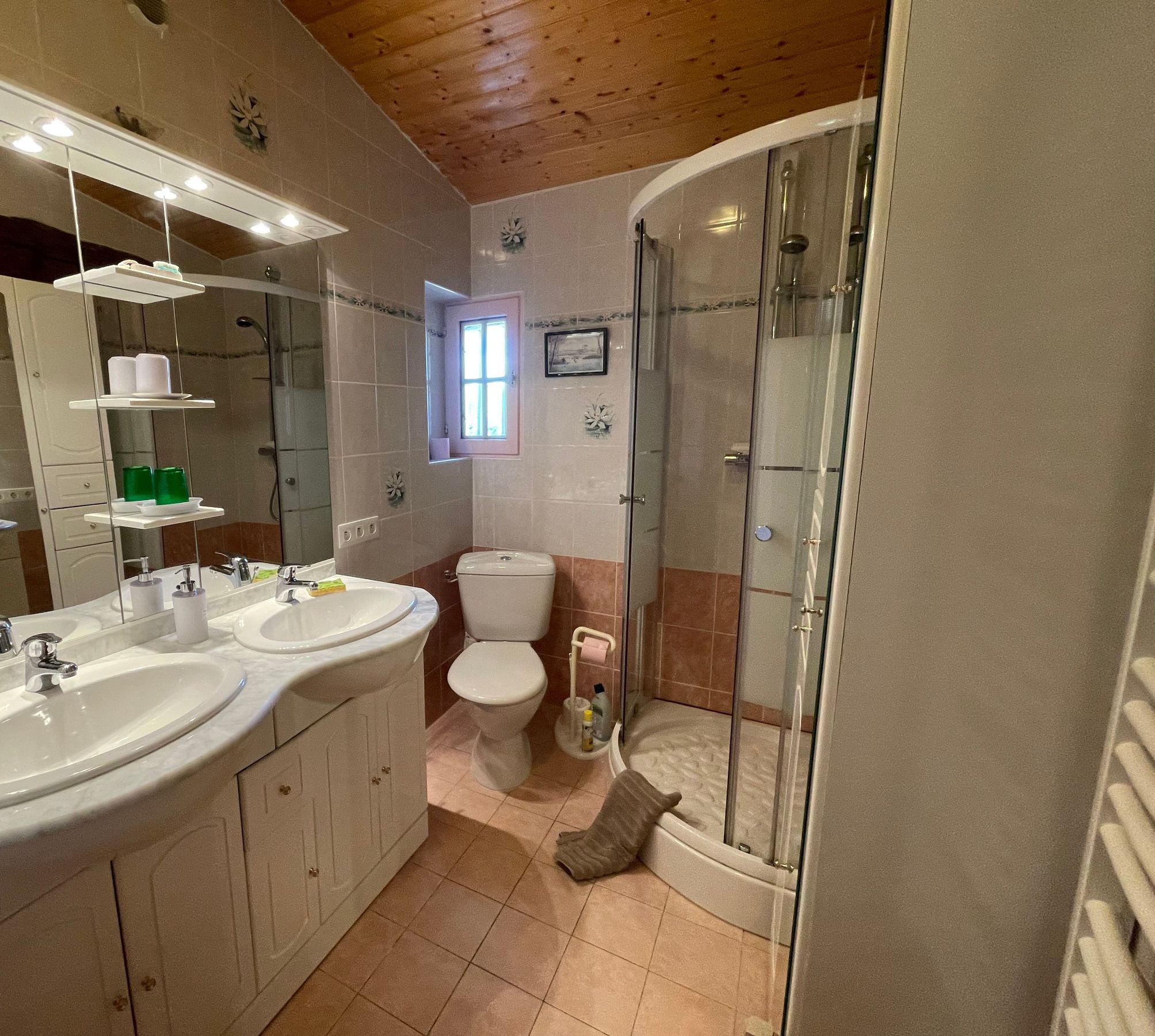 Une salle de bain avec deux lavabos, des toilettes et une douche fermée par une paroi de verre.