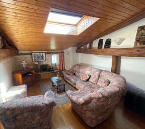 A cozy living room with wooden beams, a sofa, a coffee table, and a TV.