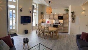 Un soggiorno ampio con una grande televisione, un'area pranzo con mobili in legno e una cucina dotata di elettrodomestici moderni.
