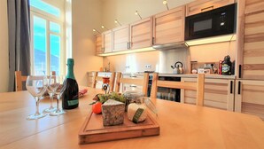 Una cucina moderna con mobili in legno, un forno a microonde e un tavolo da pranzo apparecchiato con bicchieri da vino e una bottiglia.