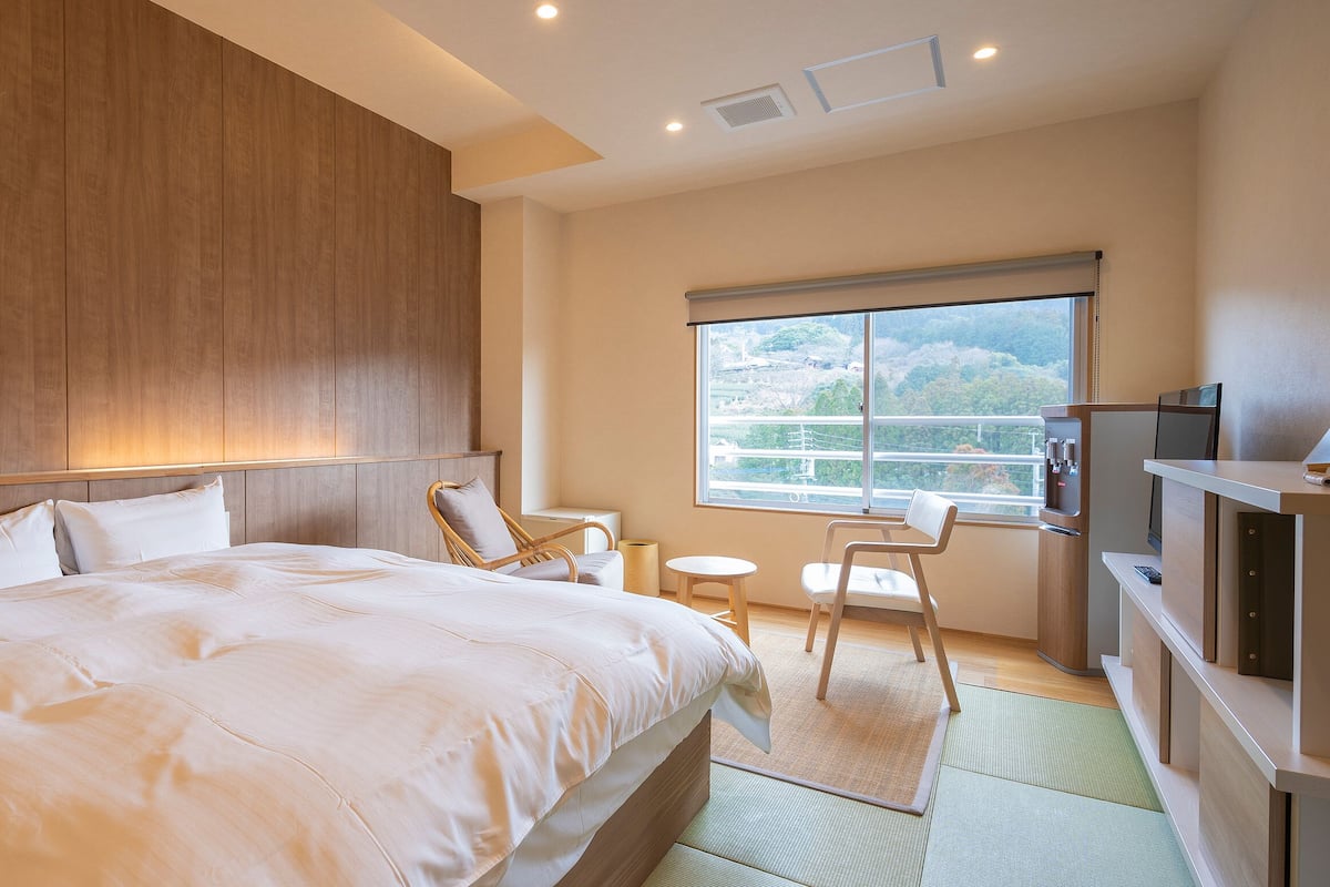 A hotel room with a large bed, a desk, a chair, and a TV.