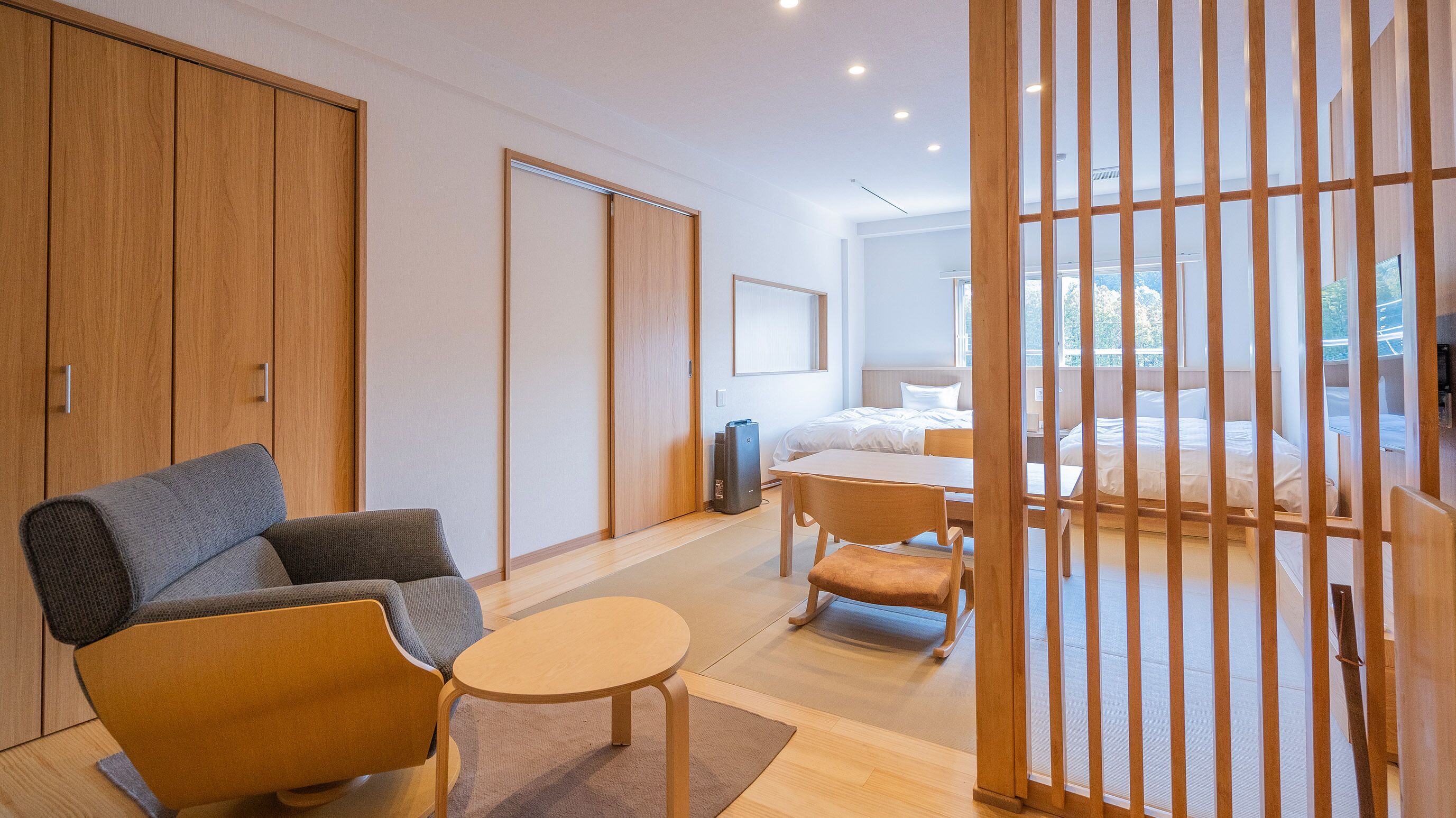 Ein modernes Hotelzimmer mit Sofa, kleinem Tisch, Bett und einer Schiebetür.