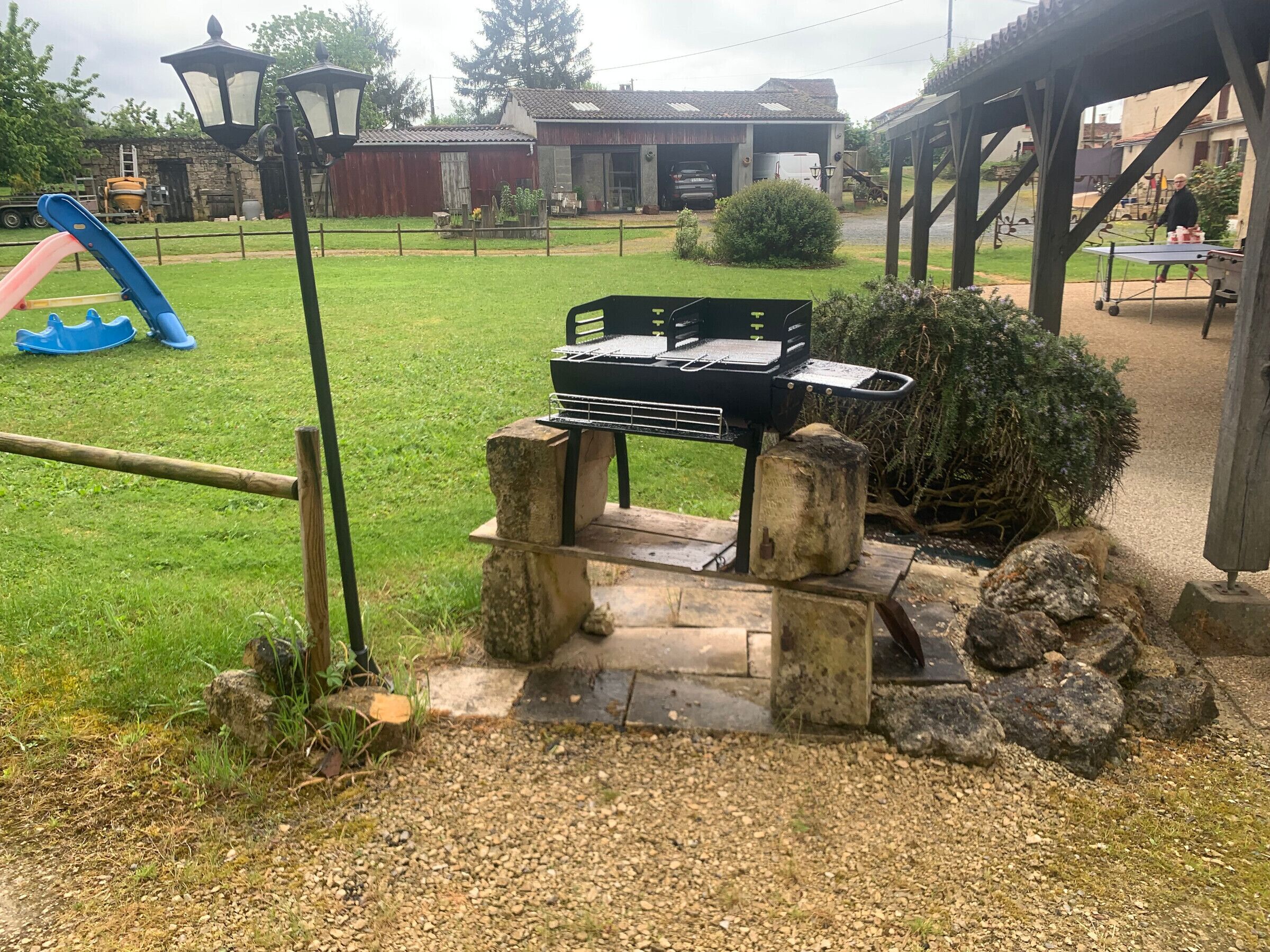 Una griglia da barbecue in una zona esterna erbosa, con un sentiero in pietra che vi conduce.