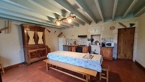 Eine rustikale Küche mit Holzschränken, einem Esstisch mit gemustertem Tischläufer und einer Sitzbank.