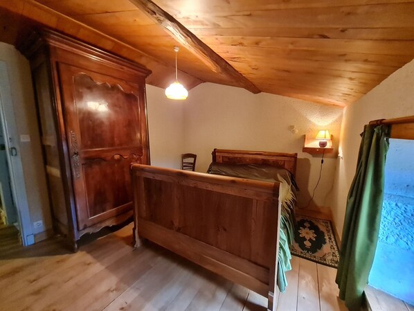 A wooden room with a bed, a wardrobe, and a hanging light fixture. - Charming 4-Bedroom Cottage with Garden, Ping-Pong, and Boat in Marais Poitevin (Benet)