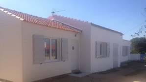 A two-story building with a red-tiled roof, white walls, and multiple windows with shutters.