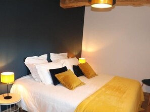 A neatly made bed with white and black pillows, a yellow throw blanket, and a small bedside table with a lamp. - 18th Century Lodge, Sleeps 10 (Les Herbiers)