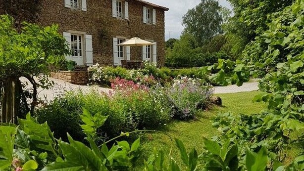 Ein Gebäude aus Stein mit einem Garten davor.