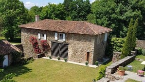 Ein Haus aus Stein mit Ziegeldach, einem kleinen Garten und einer Steinmauer.