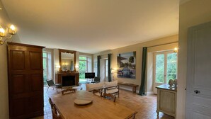 Ein großzügiges Wohnzimmer mit einem Holzesstisch, einem Kamin und einem großen Spiegel.