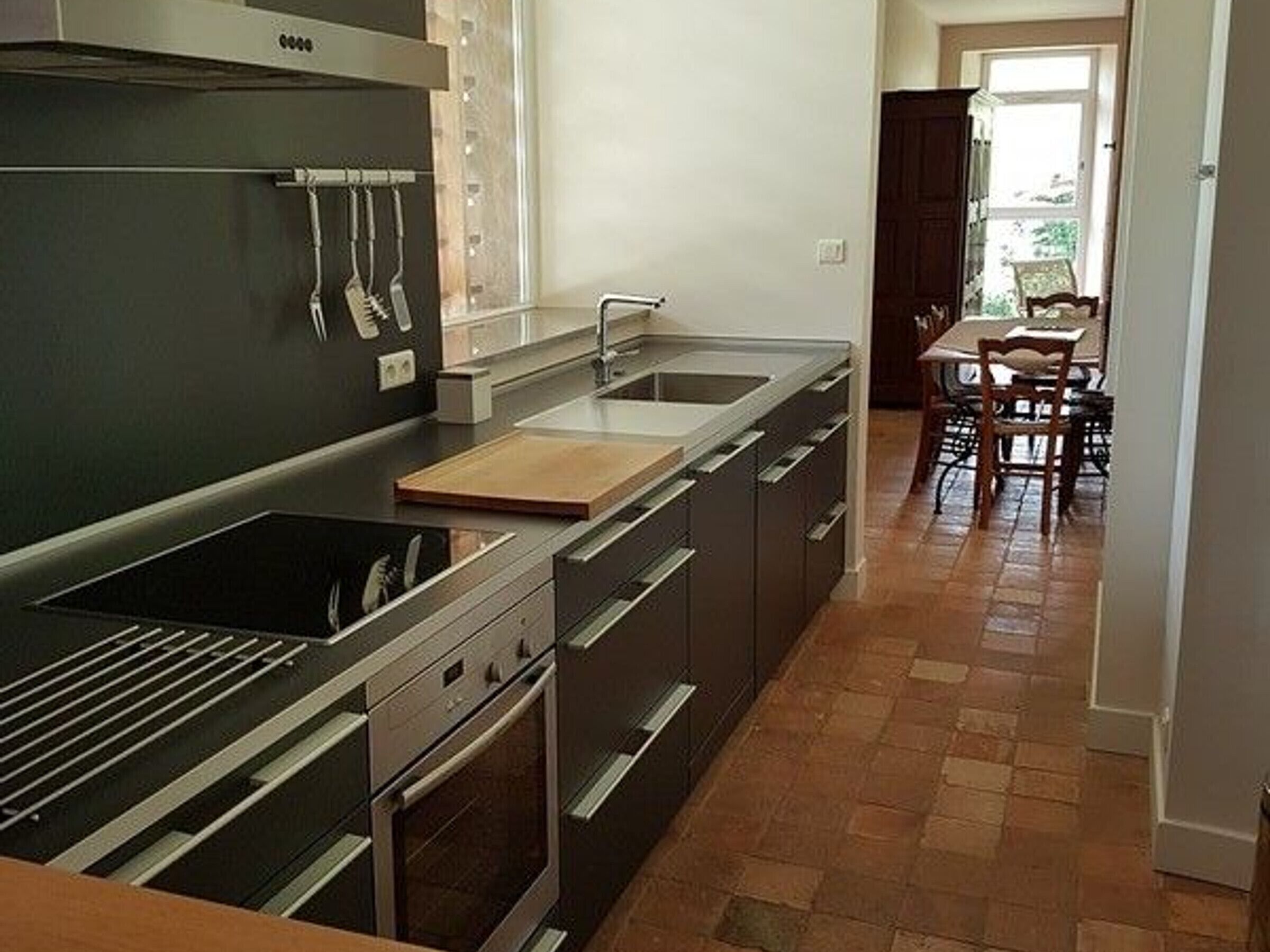 Una cocina moderna con electrodomésticos de acero inoxidable, una encimera de madera y un comedor con mesa y sillas.