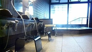 Des toilettes publiques équipées de plusieurs lavabos, d’un banc et d’une grande fenêtre laissant entrer la lumière naturelle.
