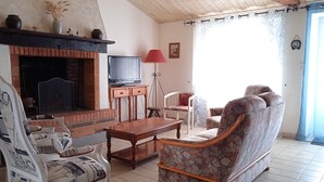 Een woonkamer met een open haard, televisie en zithoek.