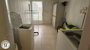 Eine kleine Küche mit Waschmaschine, Kühlschrank und Spüle.
