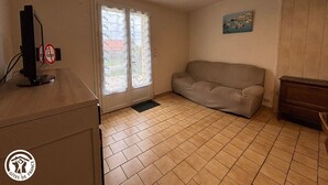 Ein Zimmer mit einem beigen Sofa, einem Holztisch mit einem Computer und einer Tür mit satinierten Glasscheiben.
