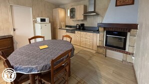 Eine kompakte Küche mit Holzschränken, einer Mikrowelle, einem Herd und einem Esstisch mit Stühlen.