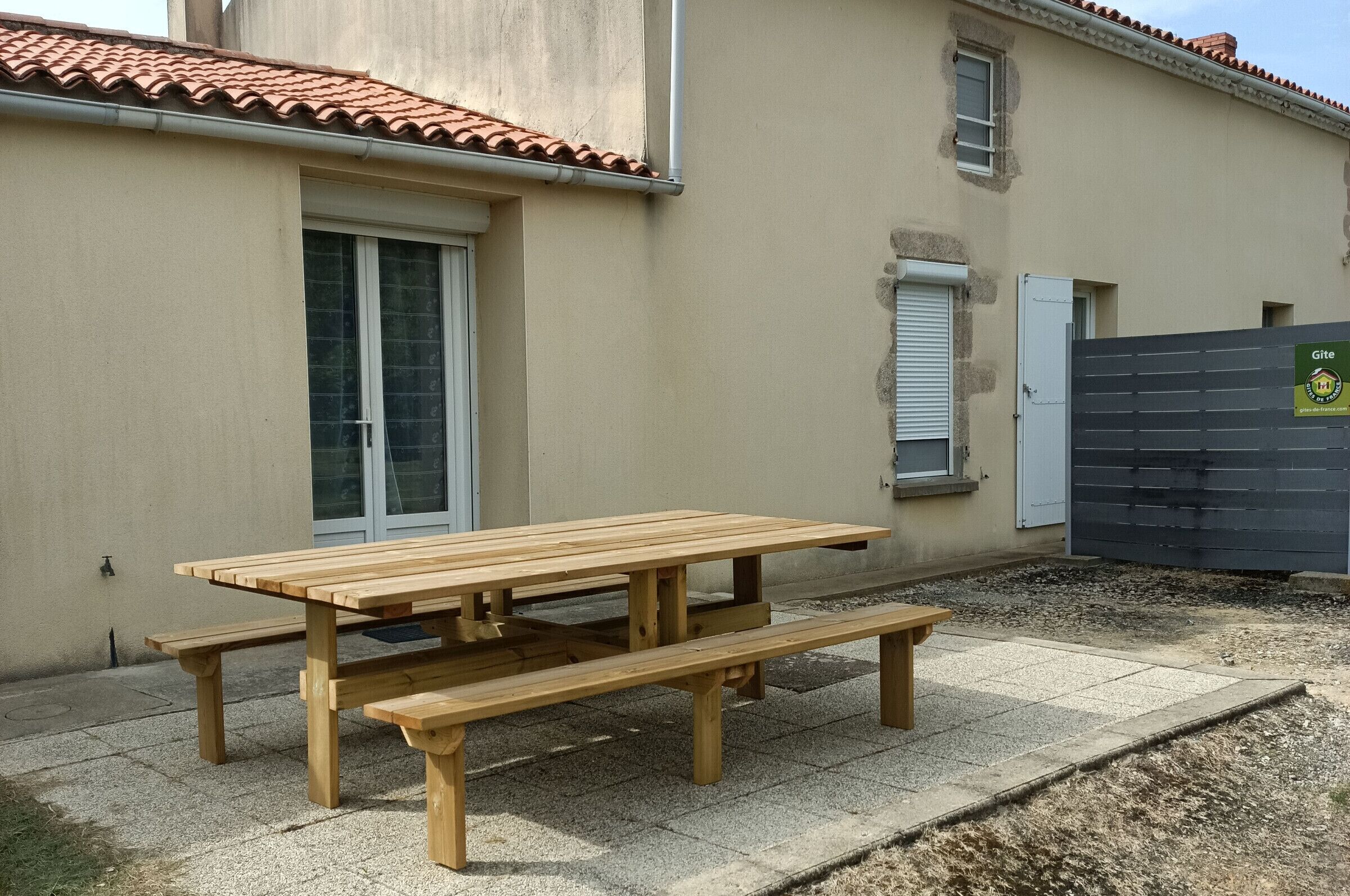 A wooden picnic table with benches in a courtyard area.