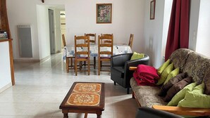 Una sala de estar con un sofá, una mesa de comedor con sillas y una mesa baja.