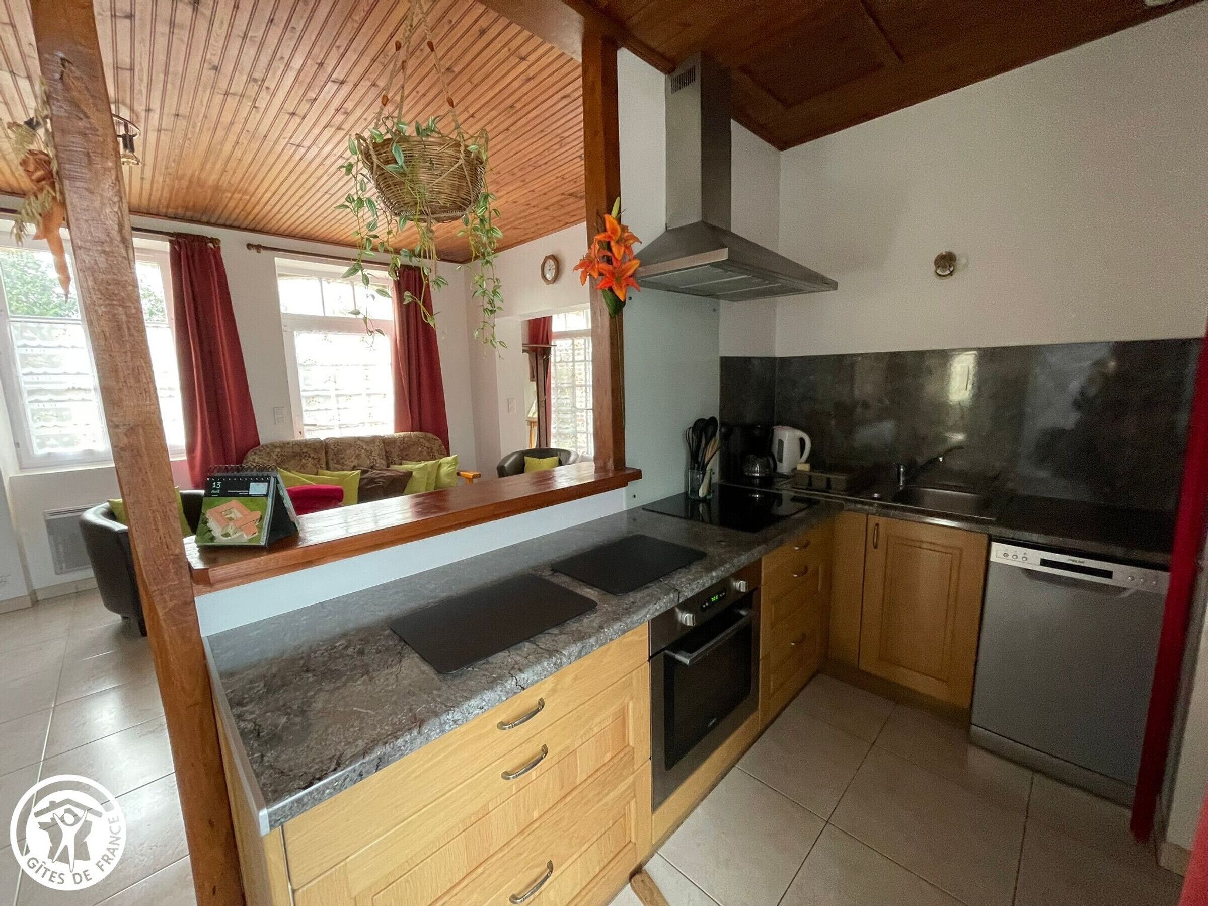 A kitchen with wooden cabinets, a black countertop, a stove, and a dishwasher.