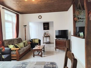 A living room with a sofa, armchairs, a coffee table, a TV, and a dining table.