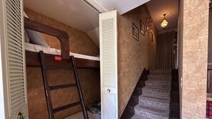 A room with a bunk bed, a wooden ladder, a white door, and a staircase with carpeted steps. - Cozy Studio for 4 in Montgenèvre – Balcony, Ski Locker, Close to Slopes & Shops (Montgenèvre)