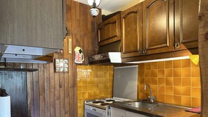 A compact kitchen with wooden cabinets, a gas stove, a microwave, and a sink. - Cozy Studio for 4 in Montgenèvre – Balcony, Ski Locker, Close to Slopes & Shops (Montgenèvre)