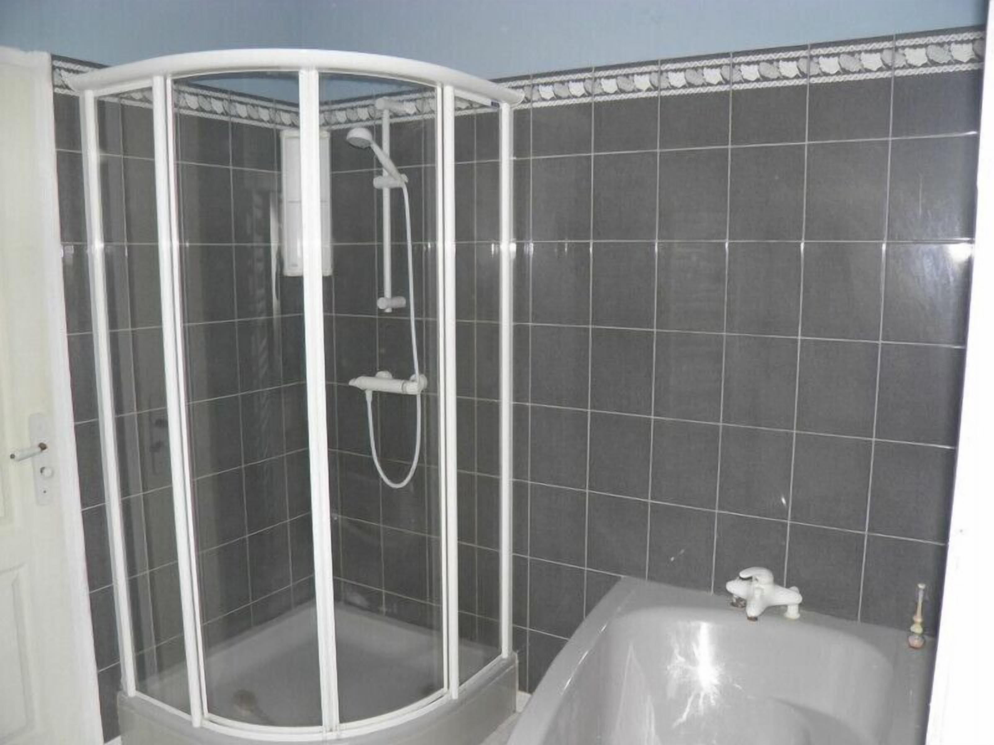 Ein Badezimmer mit Duschkabine, Badewanne und gefliesten Wänden.