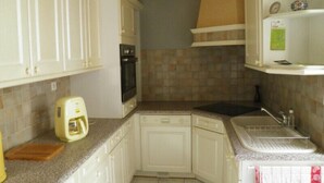 A compact kitchen with white cabinets, a built-in oven, a dishwasher, and a sink. - Charming Watermill Gîte: 6BR, Fireplace, Private Garden, Pond, Terrace, WiFi, Linens Included (Foussais-Payré)