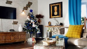 A modern living room with a fireplace, a Christmas tree, and a flat-screen TV mounted on a brick wall. - Charming Renovated Farmhouse with Private Garden, Near Fishing Pond, Trampoline, and BBQ (Brem)