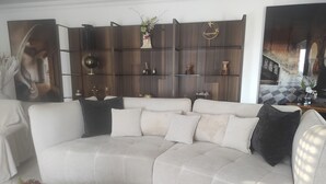 A modern living room with a sectional sofa, a decorative wall unit, and a large painting. - Spacious Farmhouse with Wi-Fi, Terraces, and Lake Access (Brem)