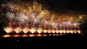 A nighttime fireworks display over a body of water with reflections on the water's surface.