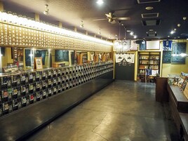 Una zona de bar con una barra larga, varios taquillones y un área de estar con mesas.