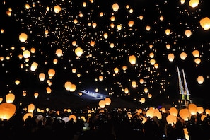 Une foule de personnes lâchant des lanternes de papier dans le ciel nocturne.