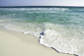 A beach with clear water and waves reaching the shore.