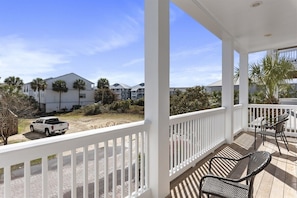 A covered outdoor area with a white railing, a patio table, and chairs.
