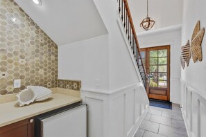 A hallway with a tiled wall, a white door, and a staircase with a wooden railing.