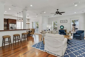 A spacious living area with a sofa, chairs, and a kitchen in the background.
