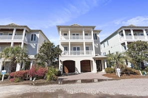 A multi-story hotel with a central entrance, balconies, and a paved driveway.