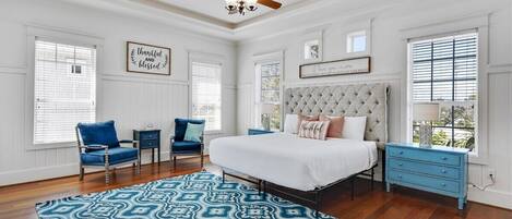 A bedroom with a tufted headboard, a patterned rug, and a ceiling fan.