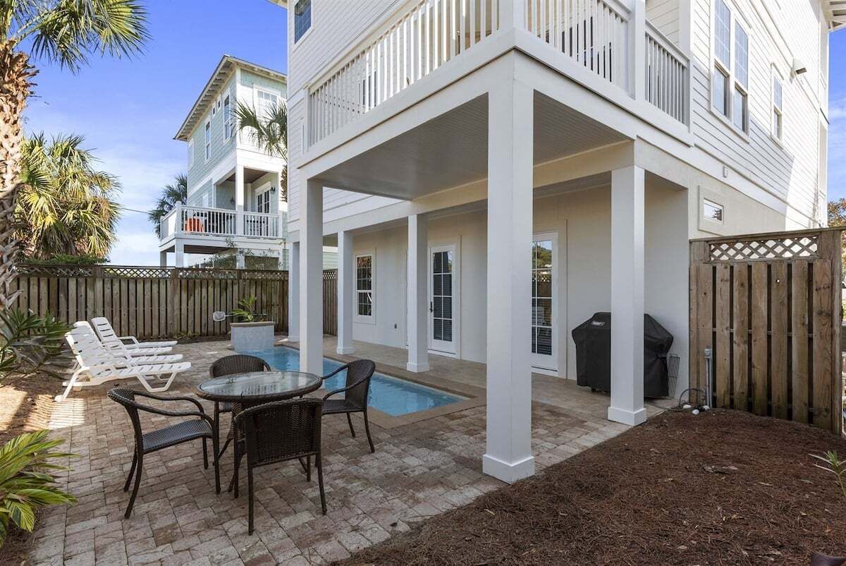 A two-story house with a covered patio, a swimming pool, and outdoor furniture.